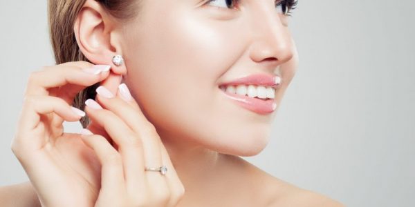 Beautiful bride in puts on diamond earring. Beauty model girl in wedding jewelry, perfect face closeup