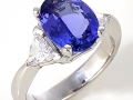 16980 - A 14 karat white gold ring with an oval brilliant cut tanzanite weighing 2.66 carats and two trillion cut diamonds totaling 0.65 carats.