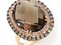 19648- A 14 karat rose gold ring set with an oval brilliant cut smoky quartz weighing 12.68 carats, champagne and white round brilliant cut diamonds totaling 0.89 carats.